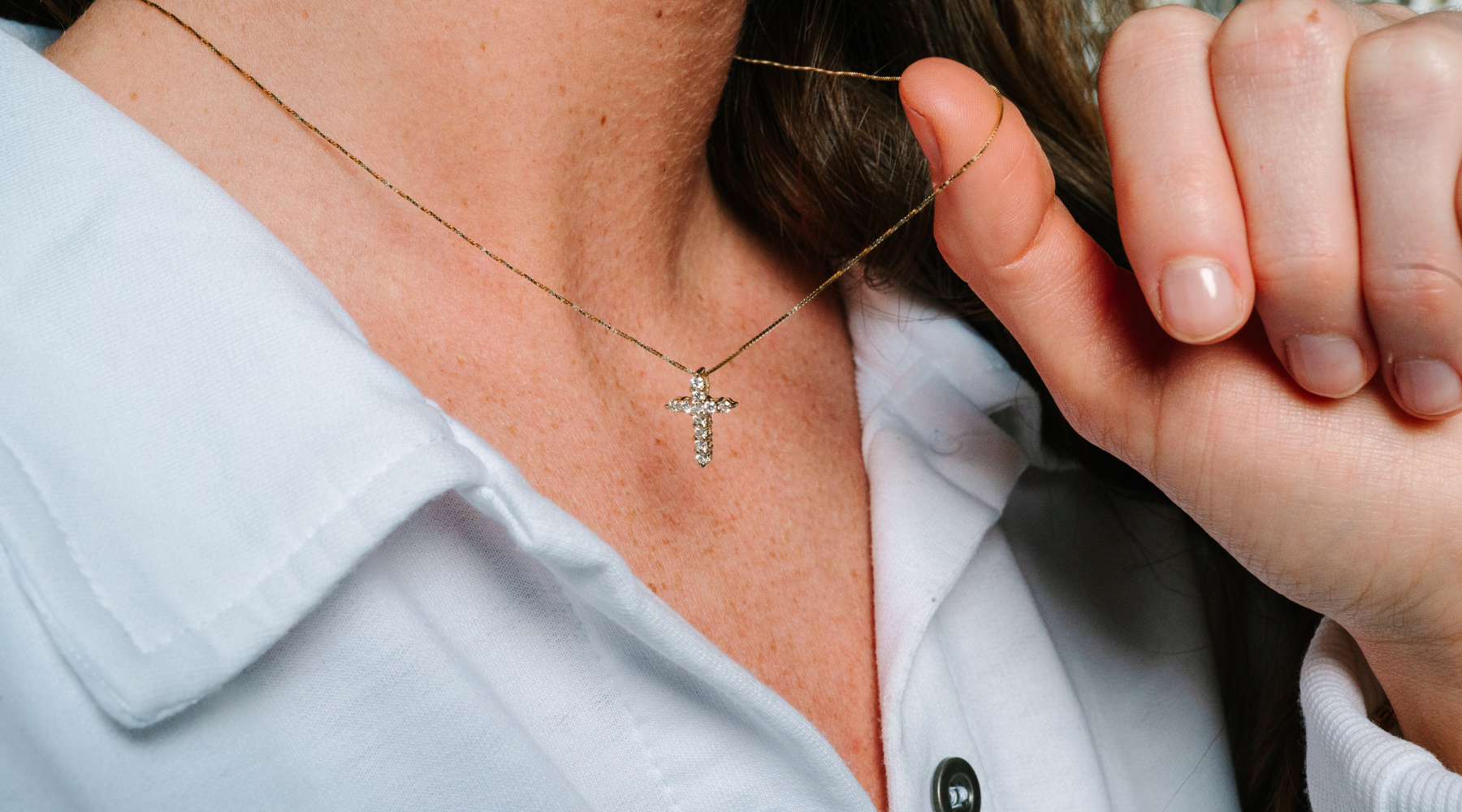 14K gold diamond cross necklace worn with white shirt, delicate chain and sparkling pendant