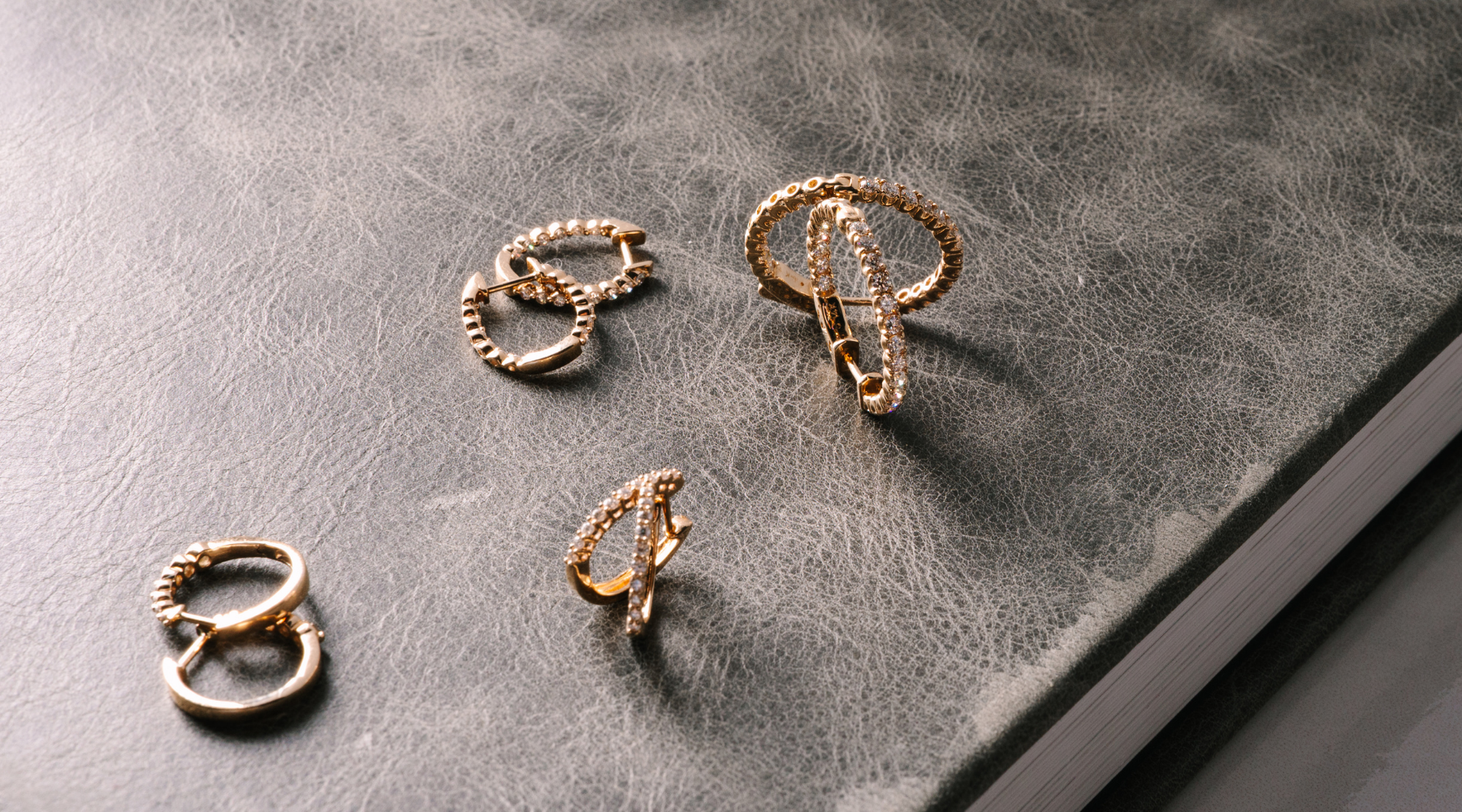 14K gold hoop earrings with diamonds, elegant fine jewelry on textured surface