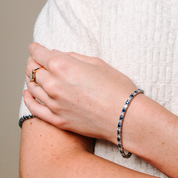Elegant 14K gold bracelet with blue sapphire and diamond accents, paired with a matching ring, worn on wrist.
