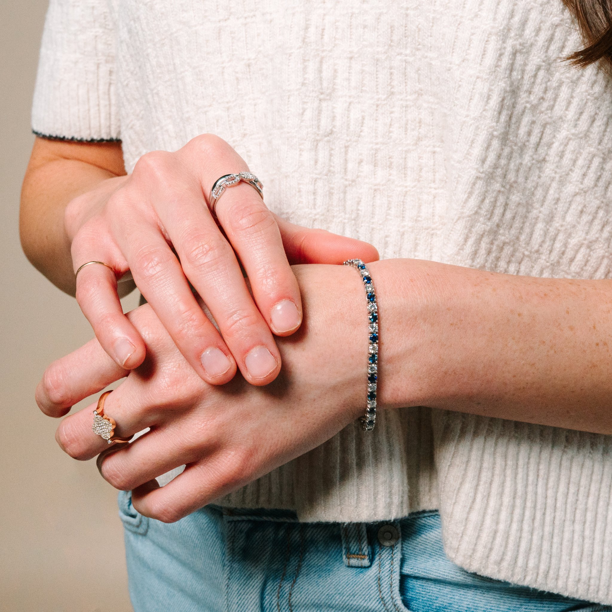 Woman wearing 14K gold diamond rings and sapphire diamond bracelet, fine jewelry for everyday wear
