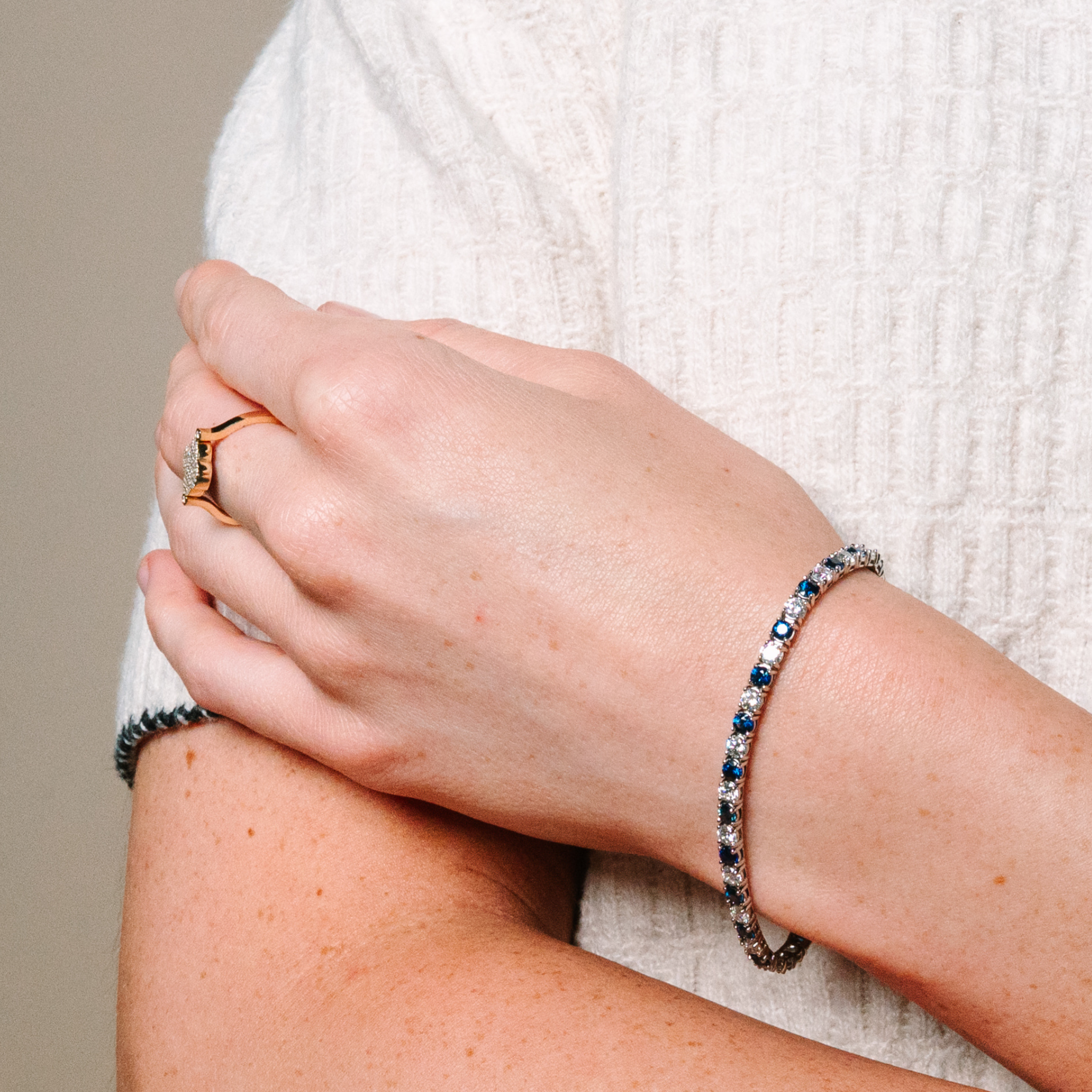 Elegant 14K gold bracelet with alternating blue sapphire and diamond accents, paired with a diamond ring on hand.