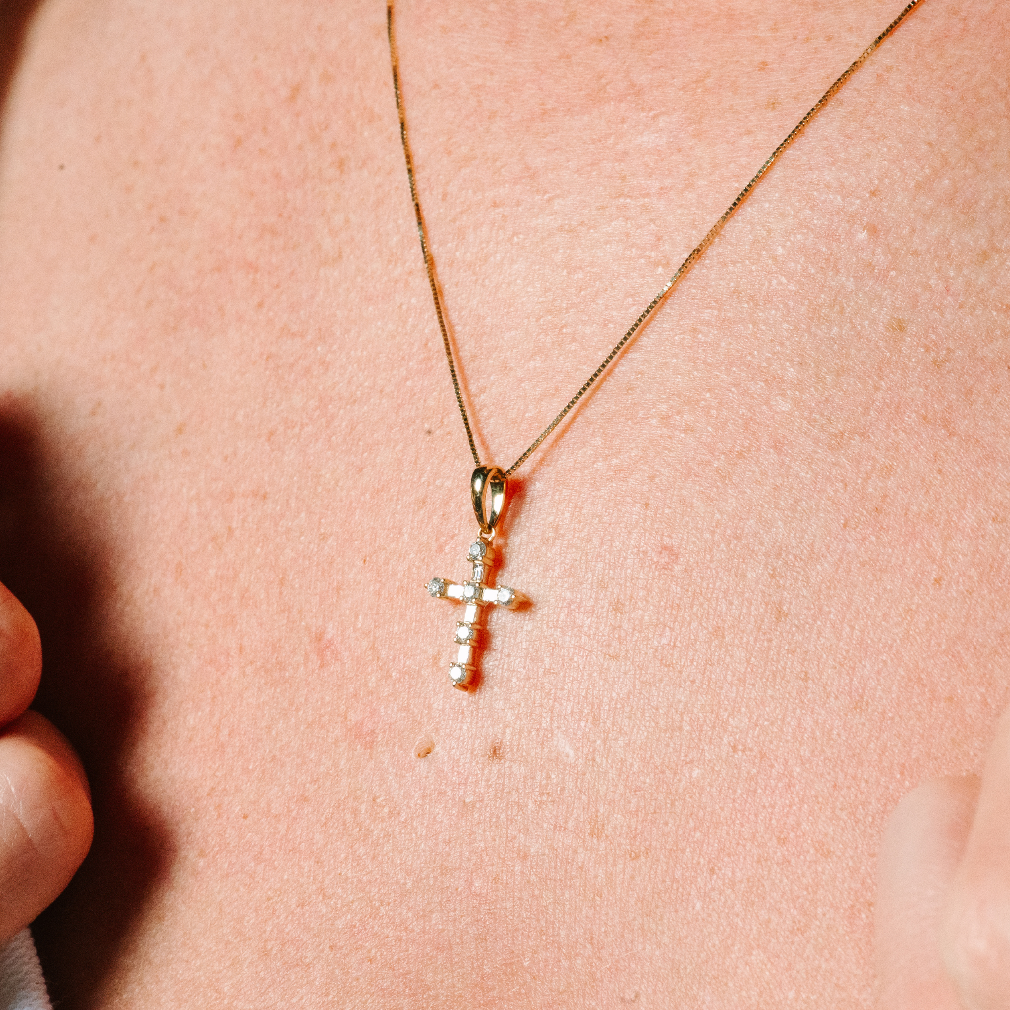 14K gold cross necklace with diamond accents, delicate chain worn on skin