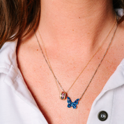 Layered 14K gold necklaces with blue butterfly pendant and colorful gemstone charm, perfect everyday fine jewelry