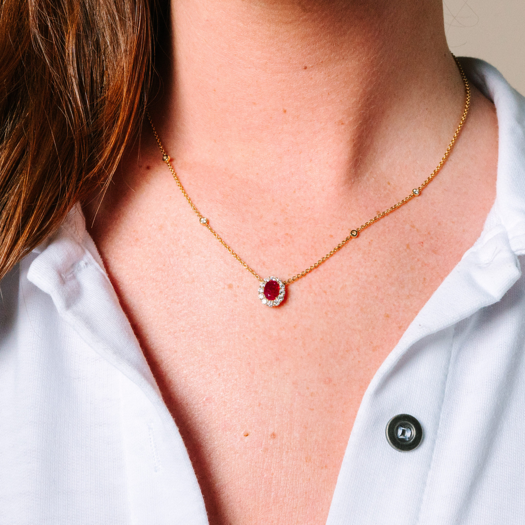 14K gold necklace with oval ruby and diamond halo, delicate chain with diamond accents, worn with white shirt