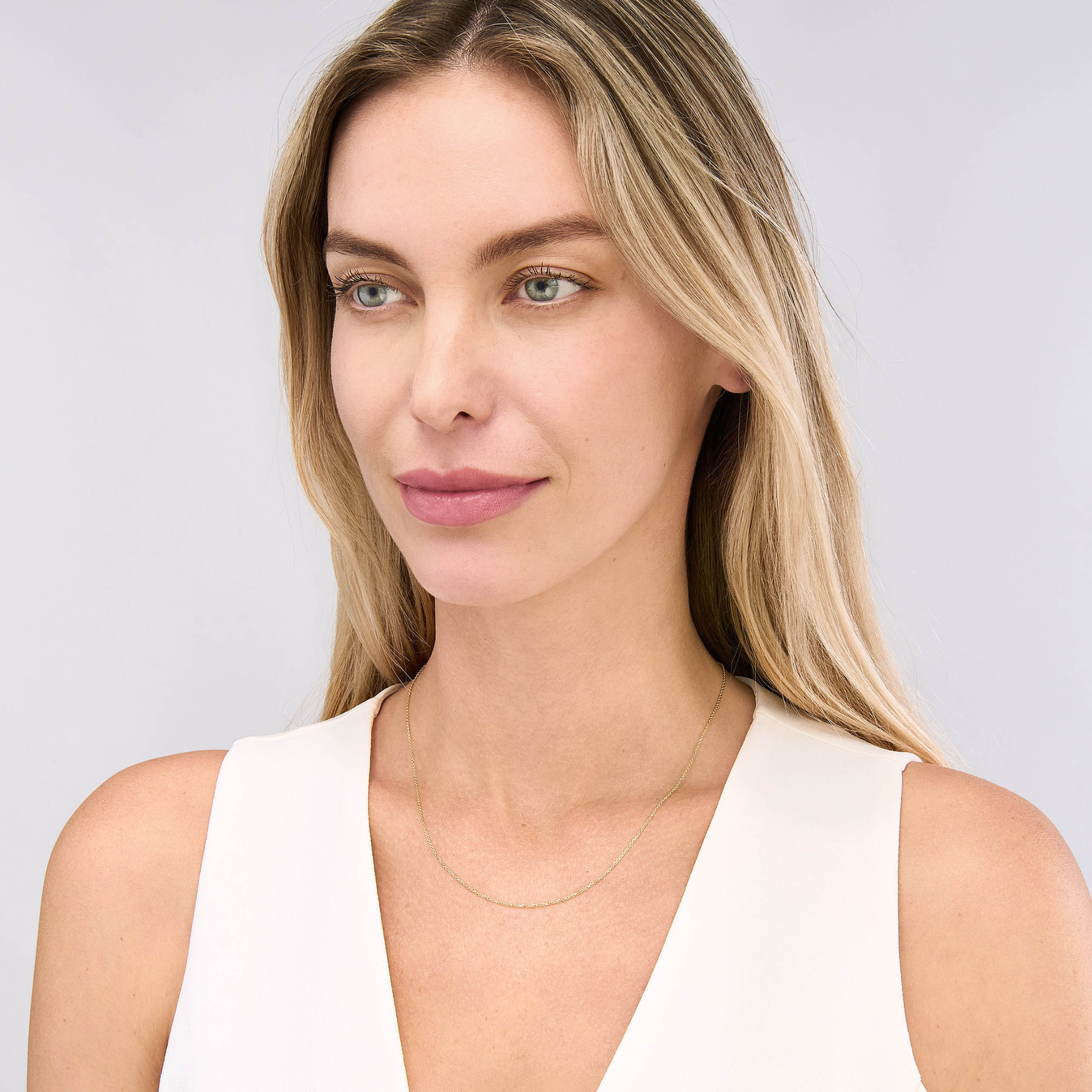 Woman wearing delicate 14K gold chain necklace, timeless fine jewelry for everyday wear