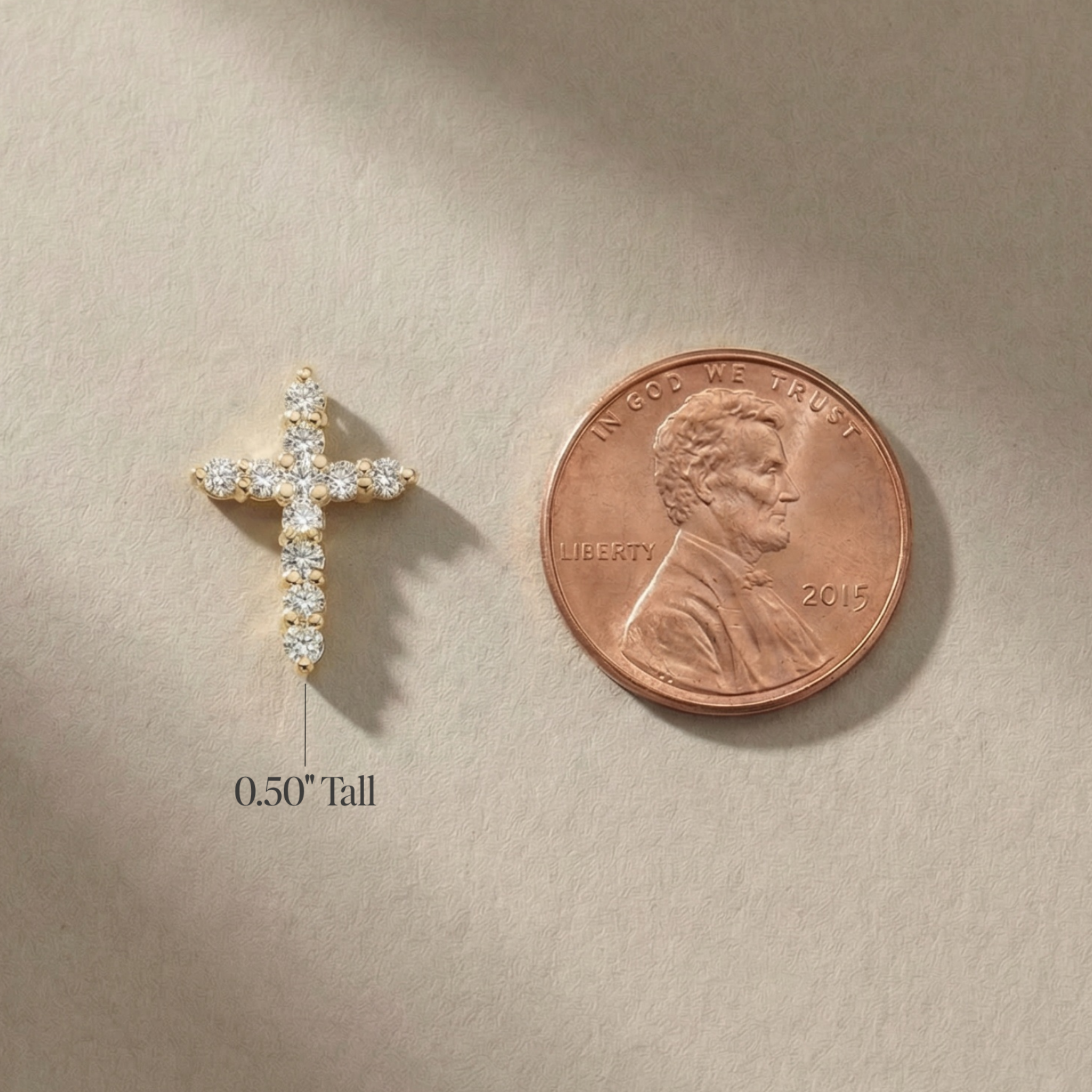 Tiny 14K gold cross pendant with diamonds, 0.50" tall, shown beside penny for scale