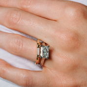 Elegant emerald cut diamond ring in 14K gold, paired with stackable bands on a hand