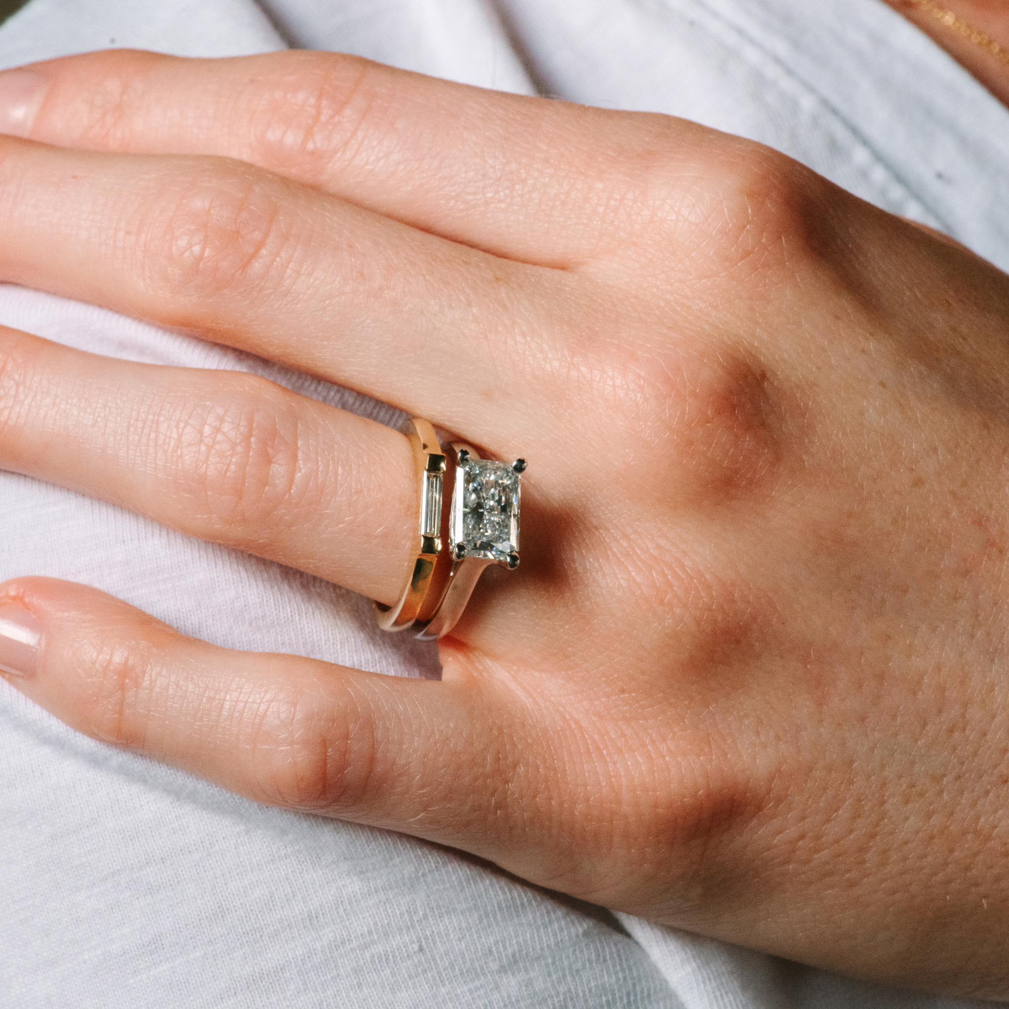 14K gold engagement ring with emerald cut diamond and baguette side stones on hand