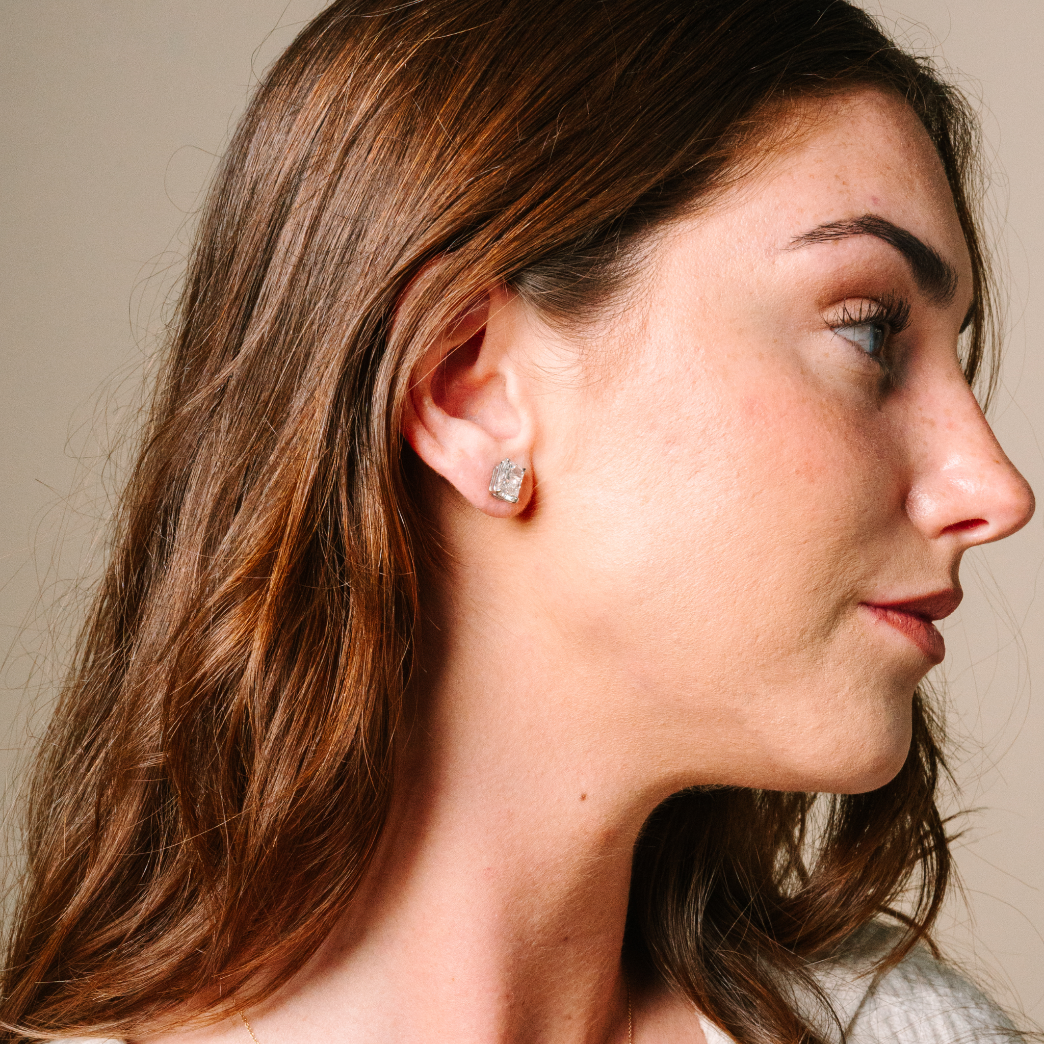 Woman wearing 14K gold emerald cut diamond stud earrings, timeless fine jewelry for everyday wear