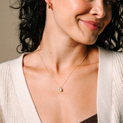 Woman wearing 14K gold necklace with emerald cut diamond pendant and matching hoop earrings