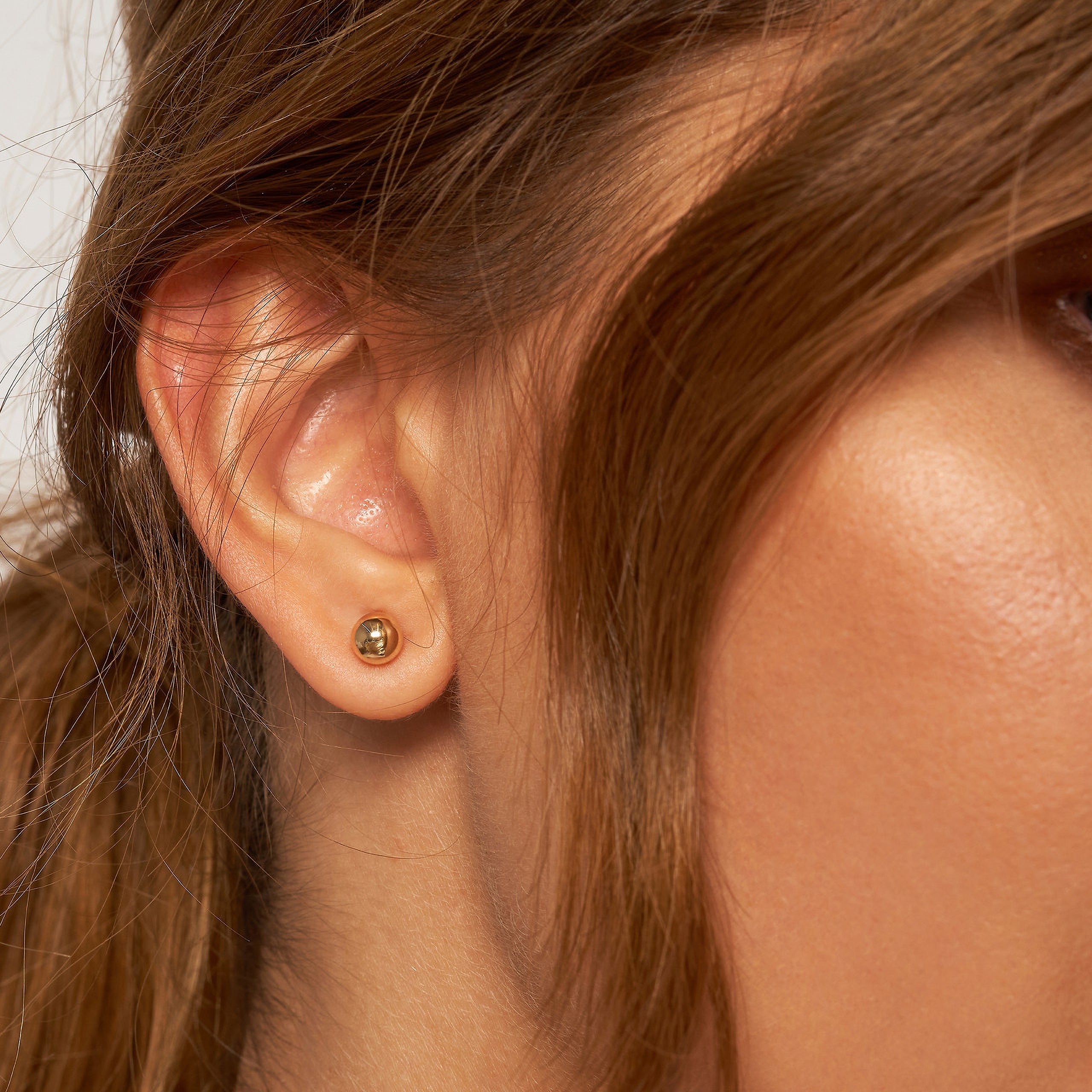 14K gold stud earring on woman's ear, minimalist fine jewelry for everyday wear