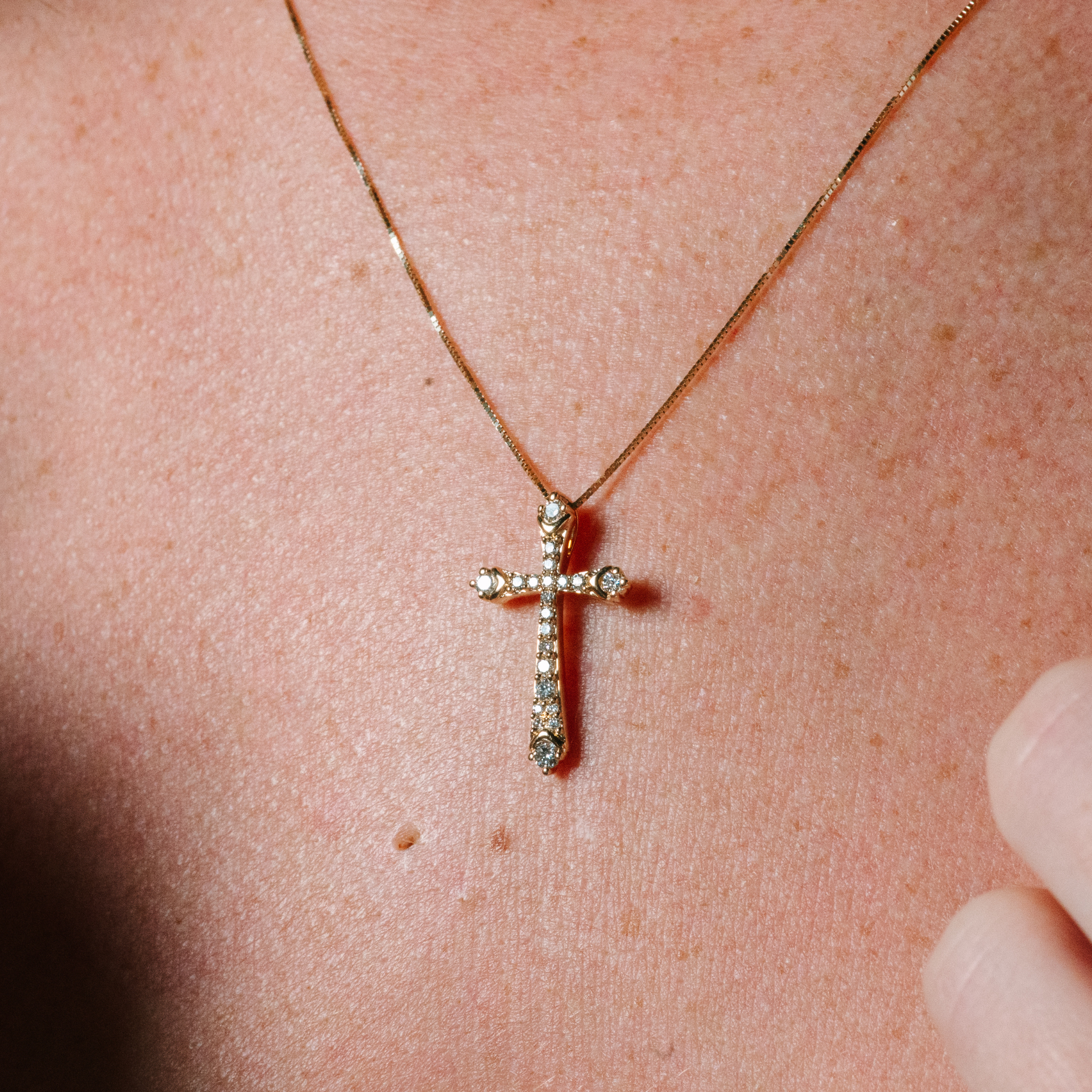 14K gold cross necklace with diamond accents, worn close-up on skin, timeless fine jewelry piece