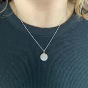 Round diamond stripe pendant necklace in 14K gold, worn on chain with dark ribbed top