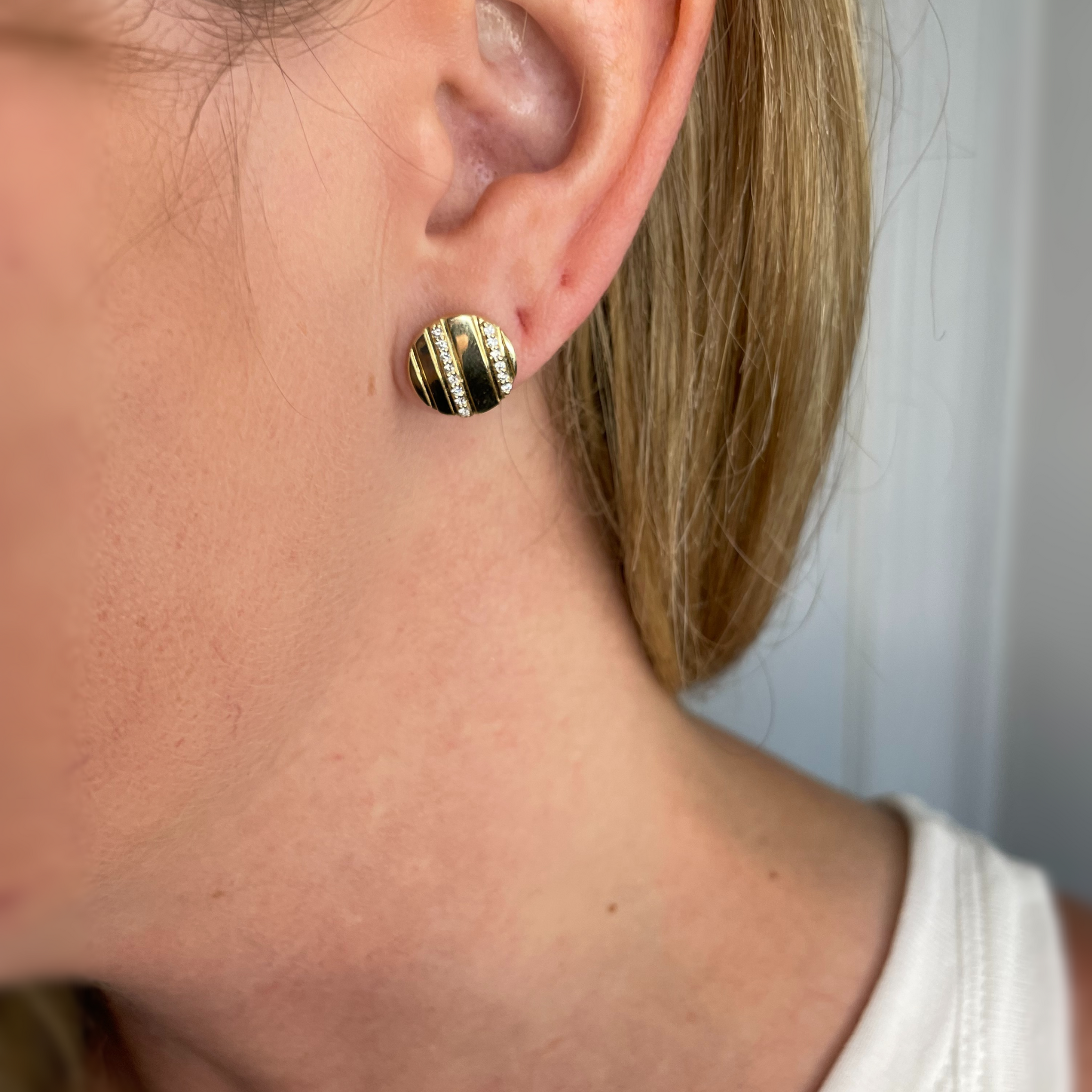 14K gold diamond stud earring with striped design, worn on ear