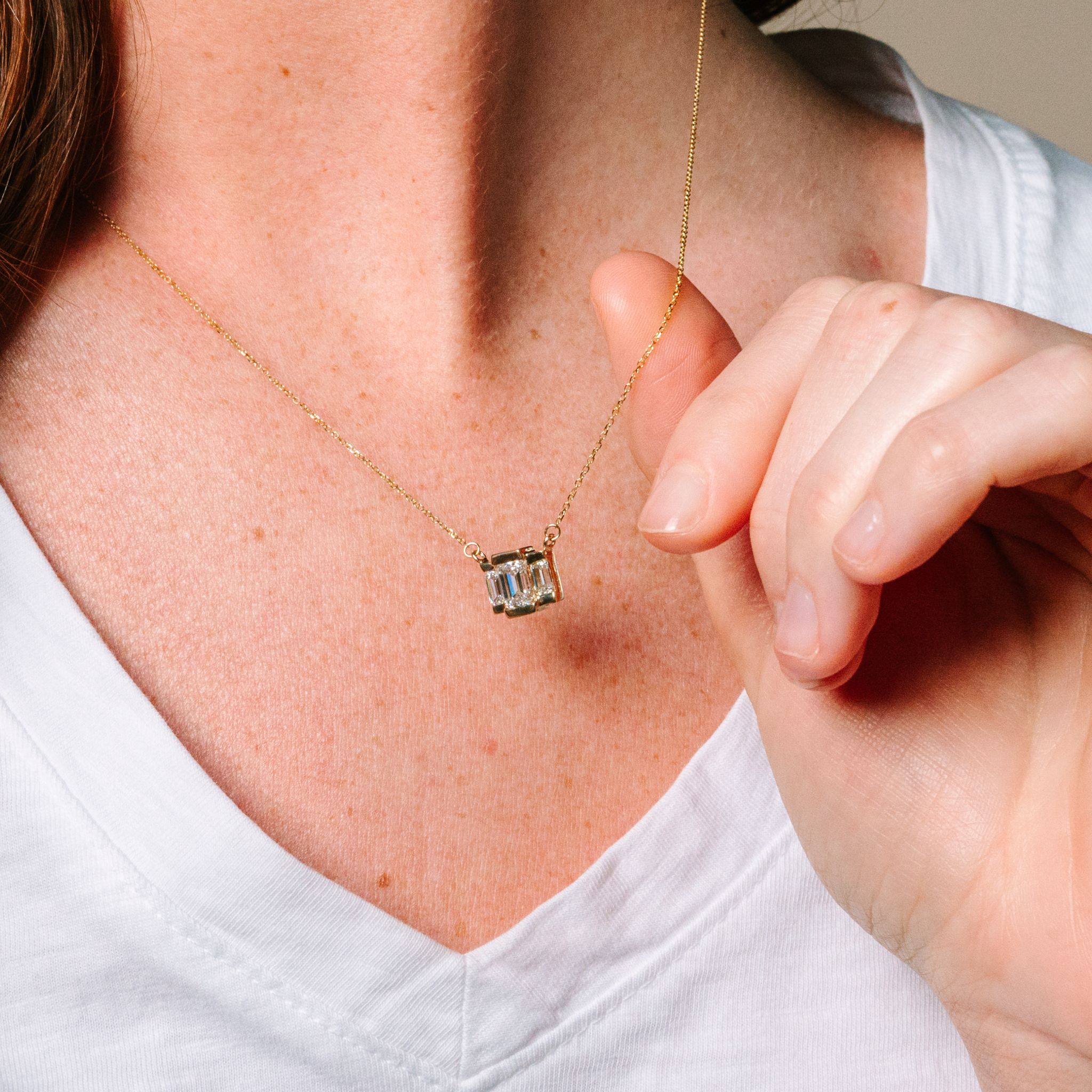 14K gold necklace with emerald cut diamond pendant, worn close-up on model