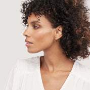 Woman wearing small gold hoop earrings, 14K gold fine jewelry for everyday wear