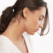Woman wearing minimalist 14K gold hoop earrings, timeless fine jewelry for everyday wear