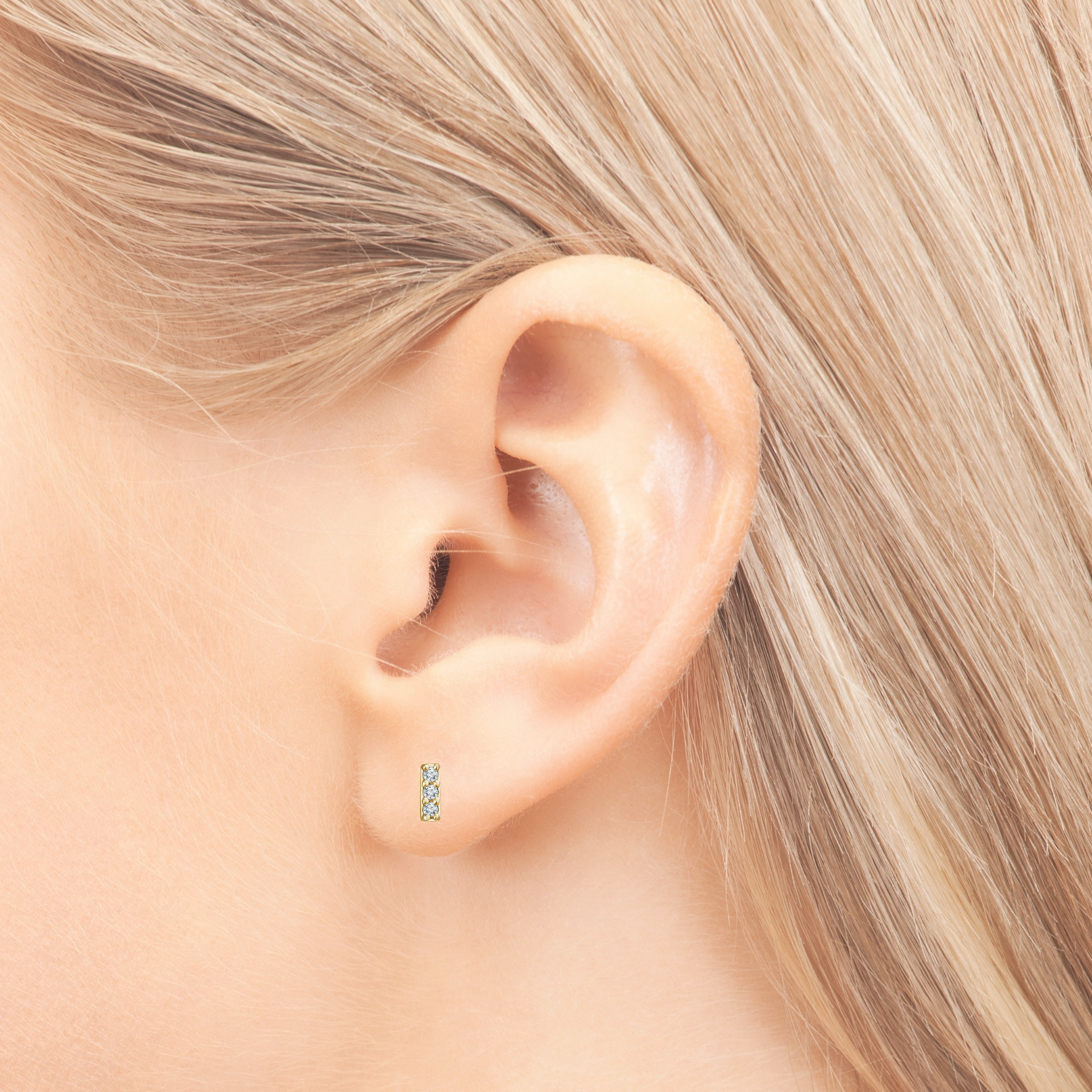 14K gold diamond stud earrings with three stones, worn on earlobe, fine jewelry for everyday wear