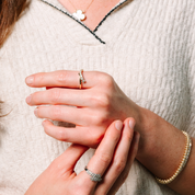 Woman wearing 14K gold diamond rings, bracelet, and cloud pendant necklace, styled for everyday elegance.