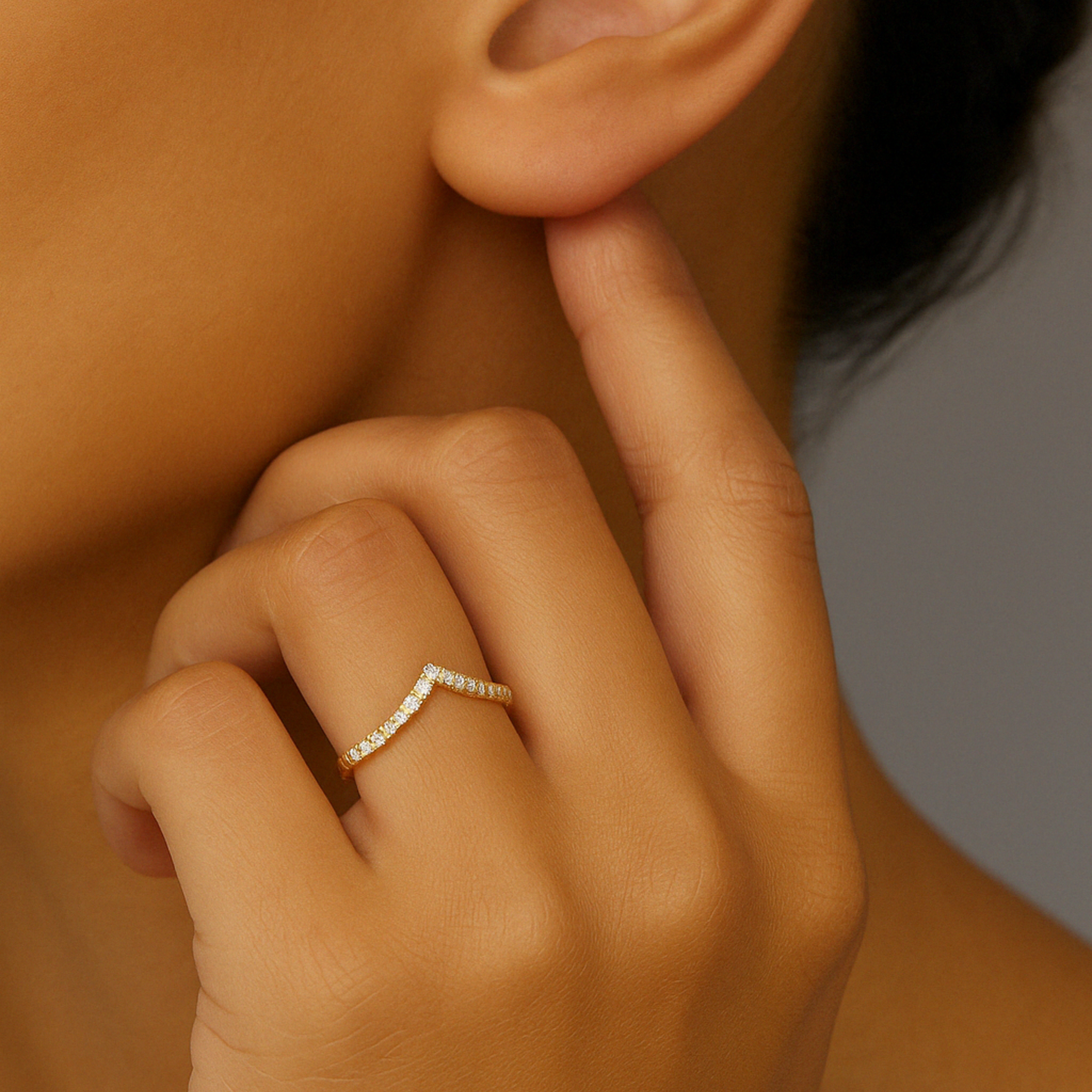 14K gold chevron ring with diamonds, worn on finger near ear, timeless fine jewelry