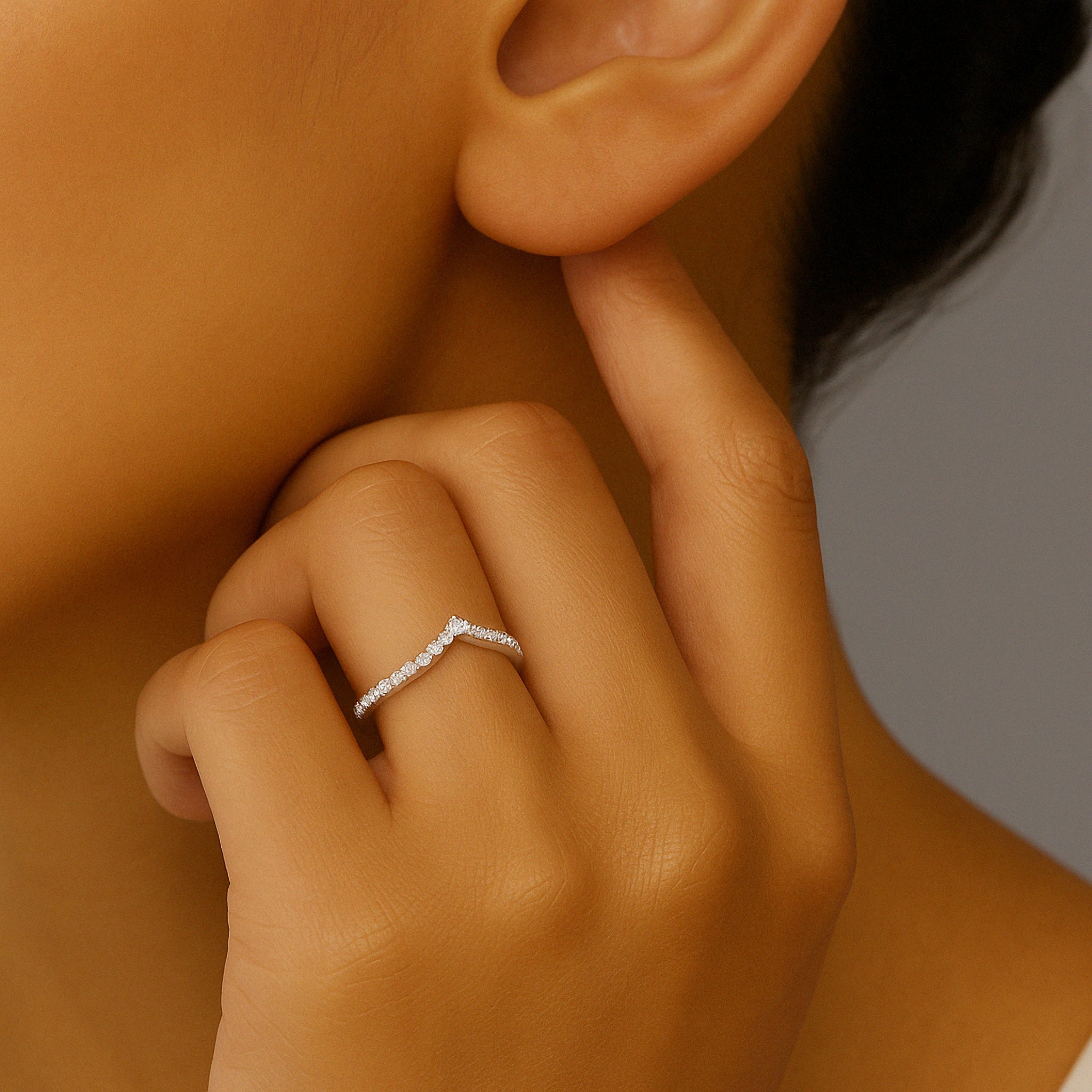 Diamond V-shaped ring in 14K gold, worn on finger near ear, elegant everyday fine jewelry