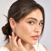 Woman wearing delicate 14K gold cross diamond stud earrings, timeless fine jewelry for everyday wear