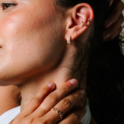 Woman wearing 14K gold diamond hoop earrings and butterfly ear cuffs, styled with delicate ring
