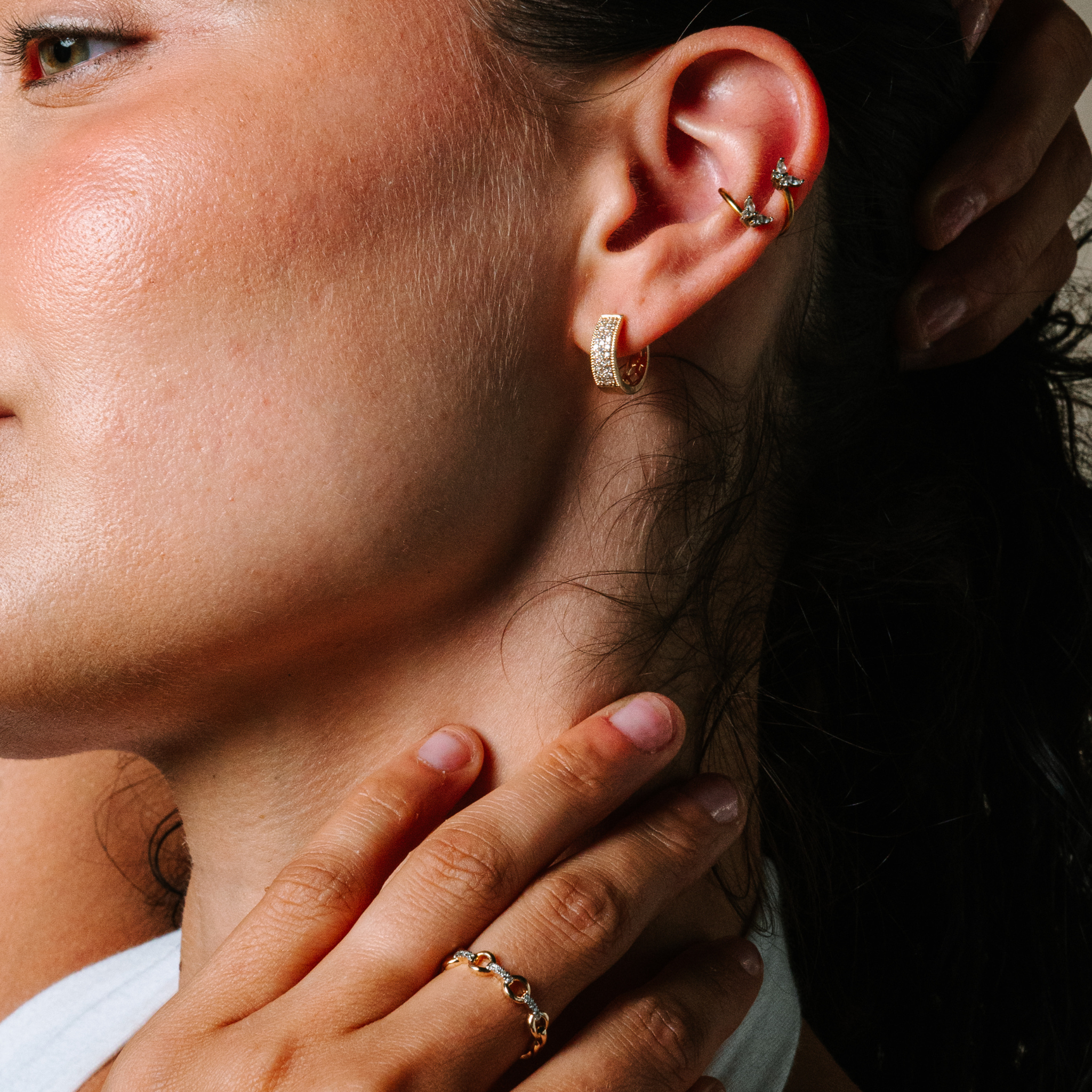 Woman wearing 14K gold diamond hoop earrings and butterfly ear cuffs, styled with delicate ring