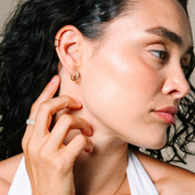 Woman wearing 14K gold diamond hoop earrings and stacking rings, showcasing timeless fine jewelry.