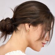 Gold hoop earring with textured design, worn by woman with low bun, showcasing everyday fine jewelry style