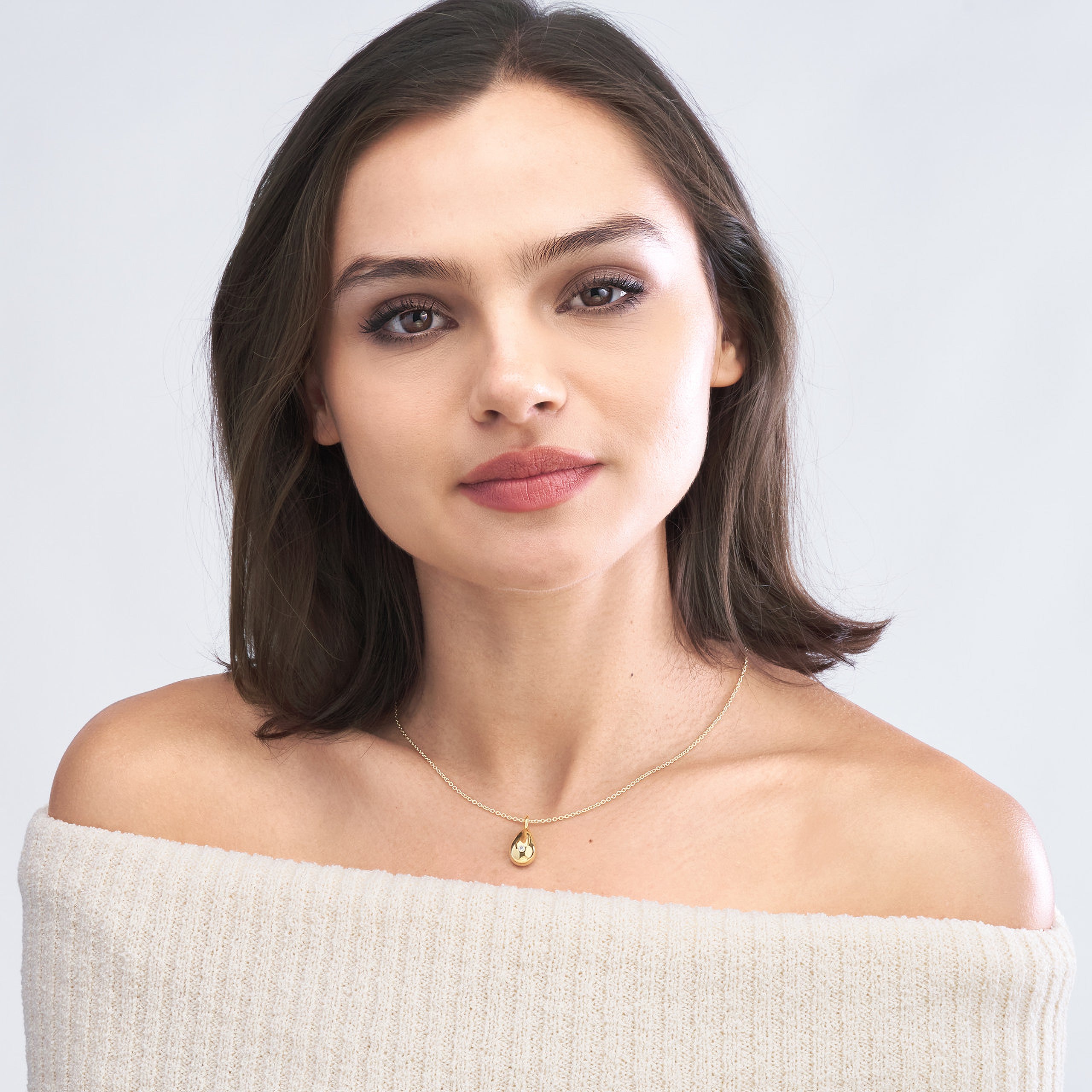 Woman wearing 14K gold teardrop necklace with diamond, fine jewelry for everyday wear