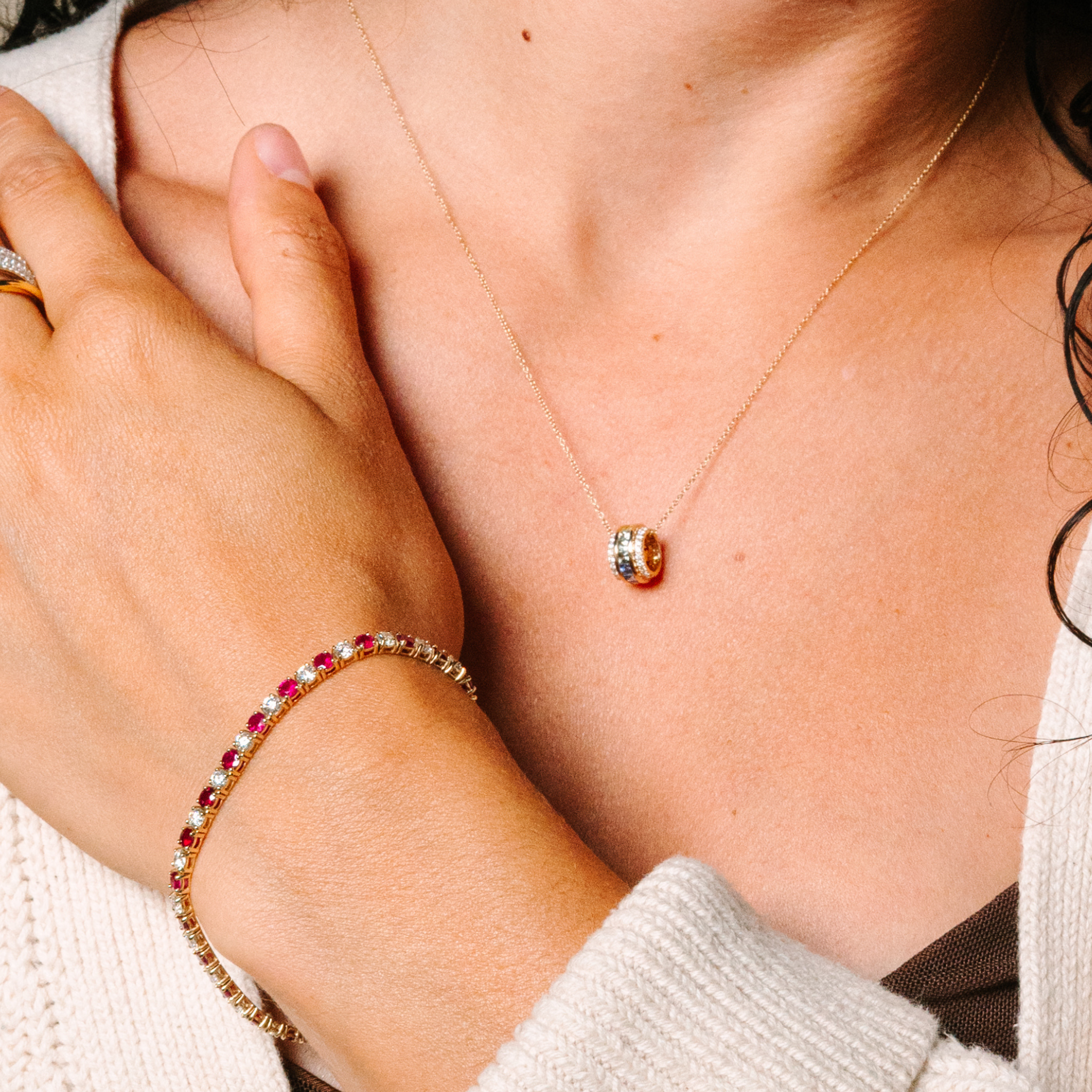Woman wearing 14K gold necklace with diamond pendant and ruby diamond bracelet, fine jewelry for everyday wear