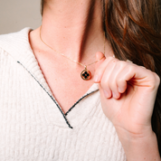 14K gold necklace with black flower pendant, worn with white textured top