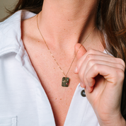 14K gold necklace with square pendant featuring star and gemstone details, worn with white shirt
