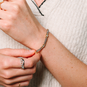 Woman adjusting 14K gold diamond chain bracelet with diamond rings on fingers, fine jewelry for everyday wear