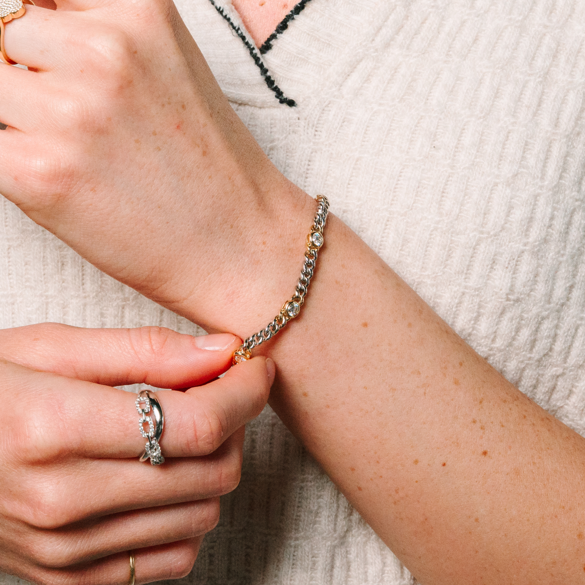 Woman adjusting 14K gold diamond chain bracelet with diamond rings on fingers, fine jewelry for everyday wear