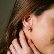 Diamond hoop earring in 14K gold, worn on ear with hand gently touching neck